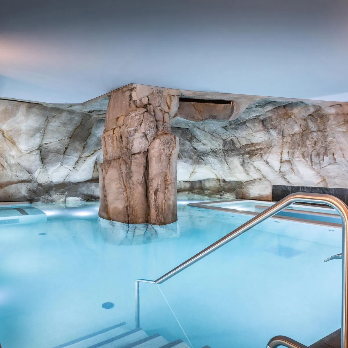 Innenpool mit großer Felswand und Metalltreppen für den Zugang