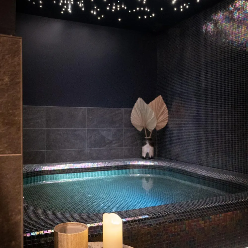 Indoor pool lit by a candle and a vase on a nearby table