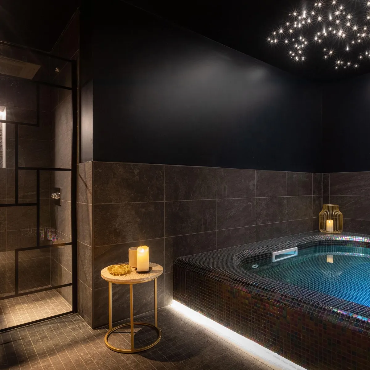 Luxurious bathroom with built-in bathtub, candles, and starry ceiling lighting