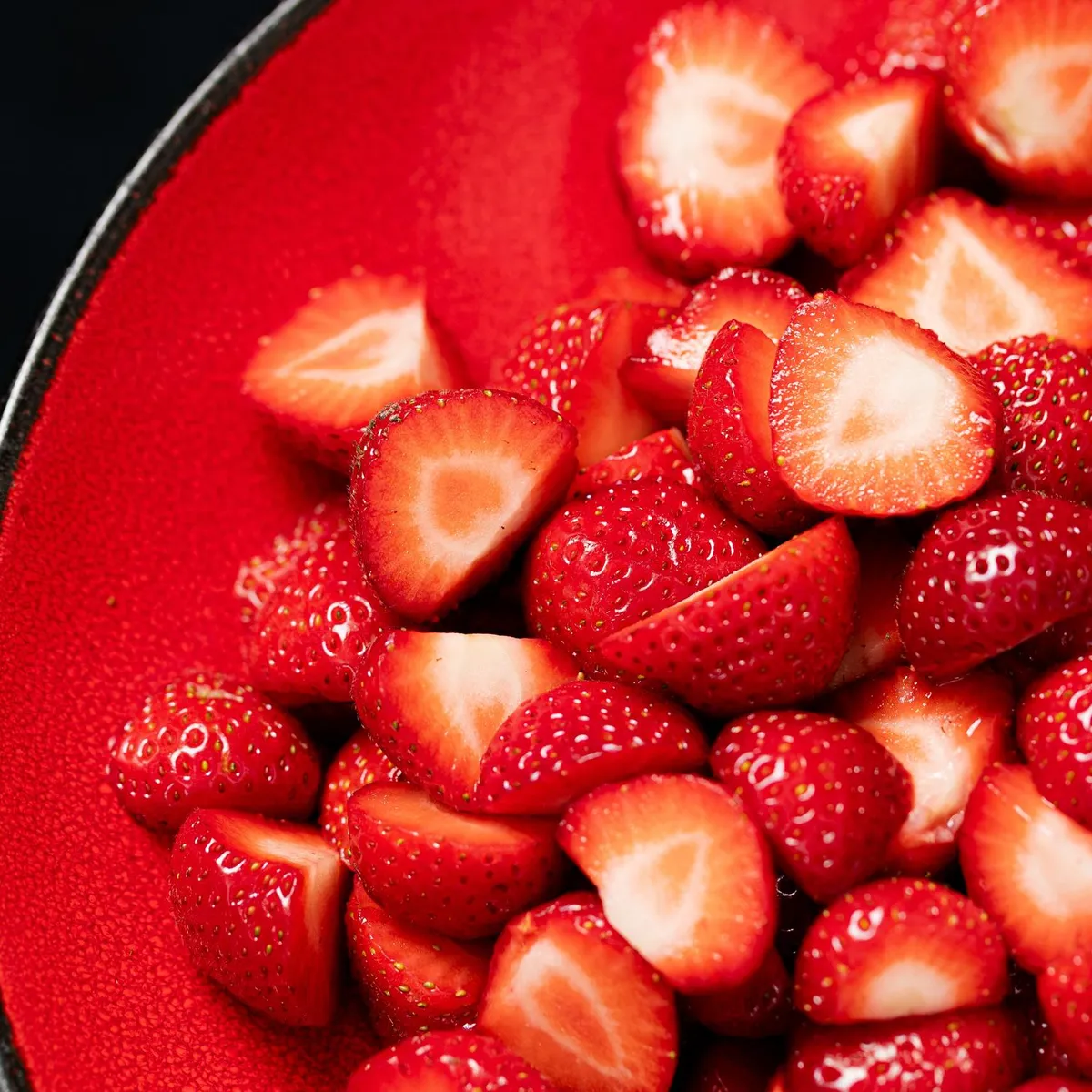 Pieces of strawberries cut in half in a red dish