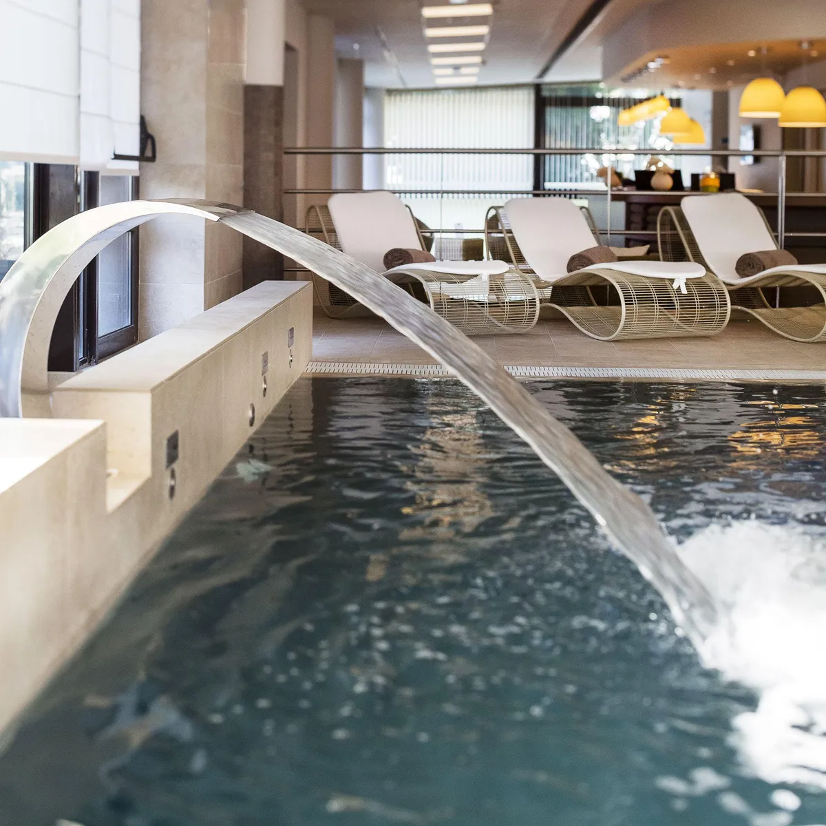 Indoor pool with sun loungers and a relaxation area in the background