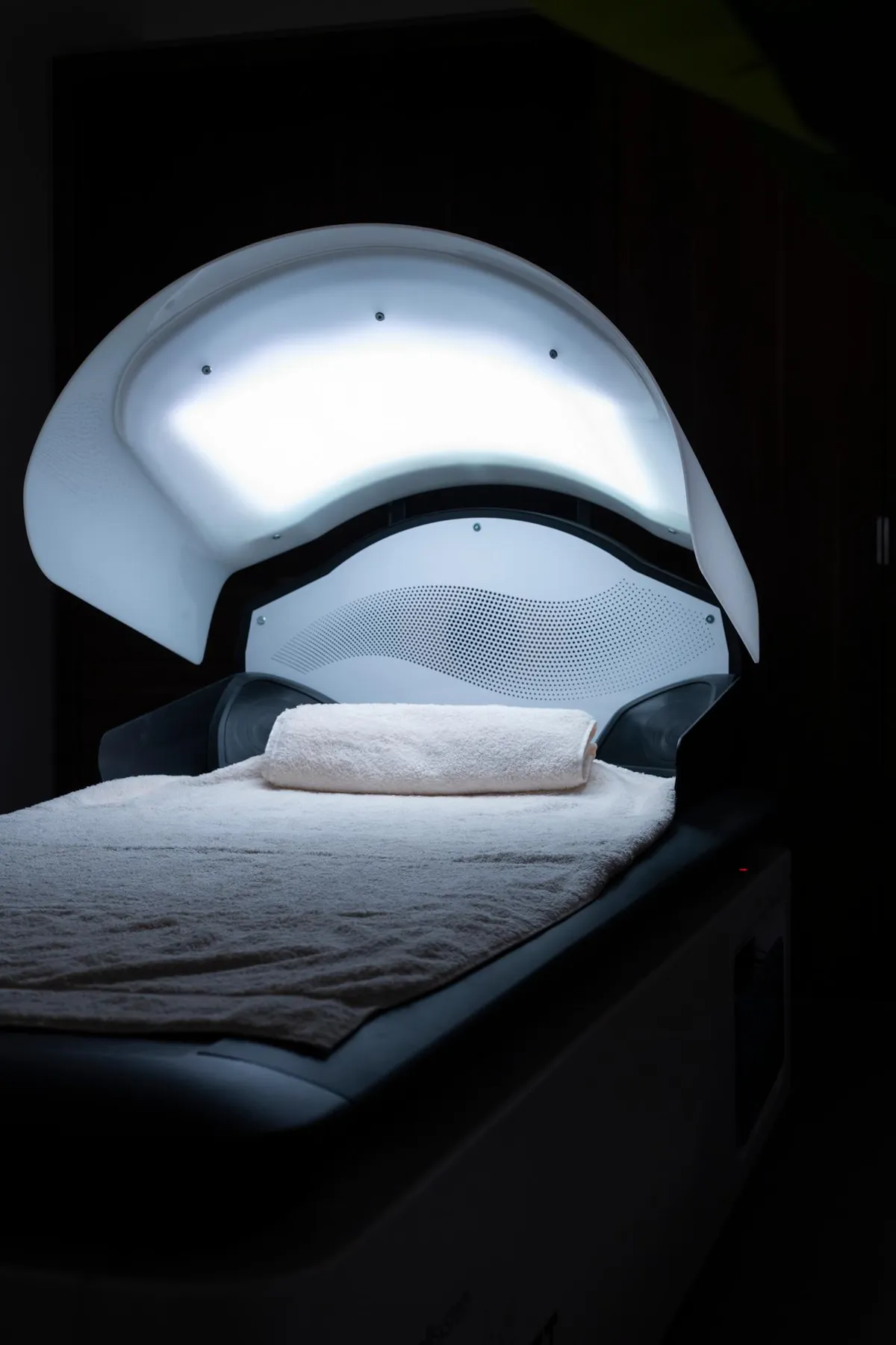 Luminotherapiegerät mit eingeschaltetem weißem Licht und einem zusammengerollten Handtuch auf einem Kissen