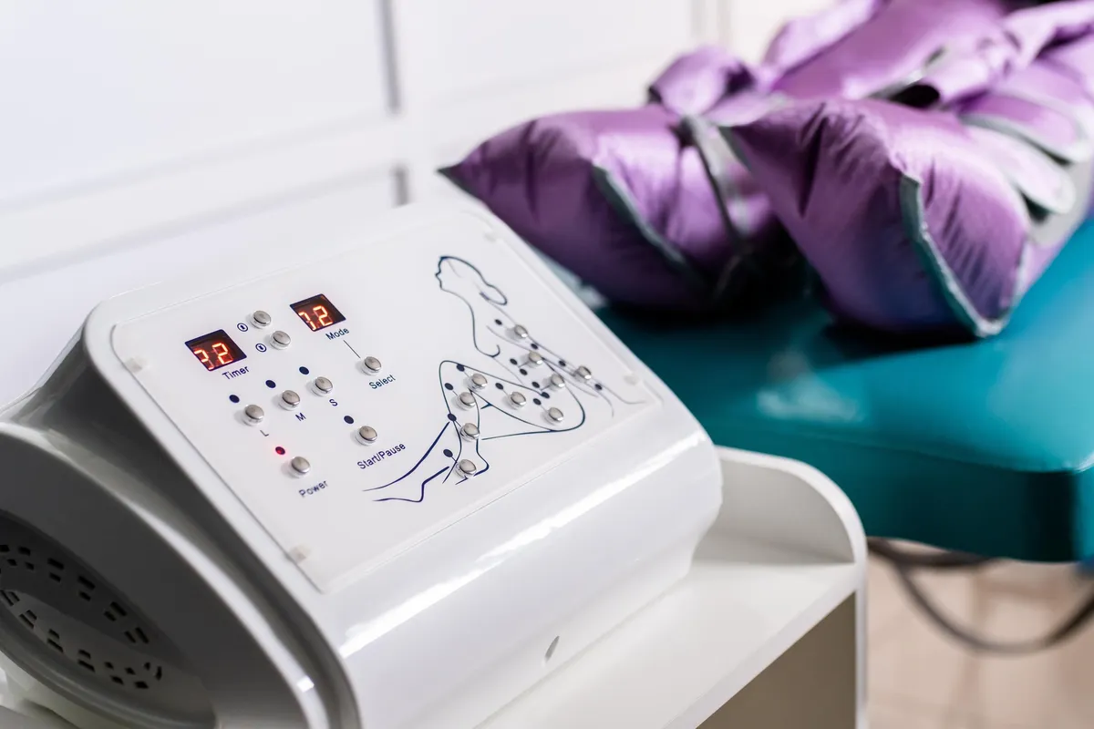 Medical device with digital screen and control buttons, placed on a table with a purple cushion in the background