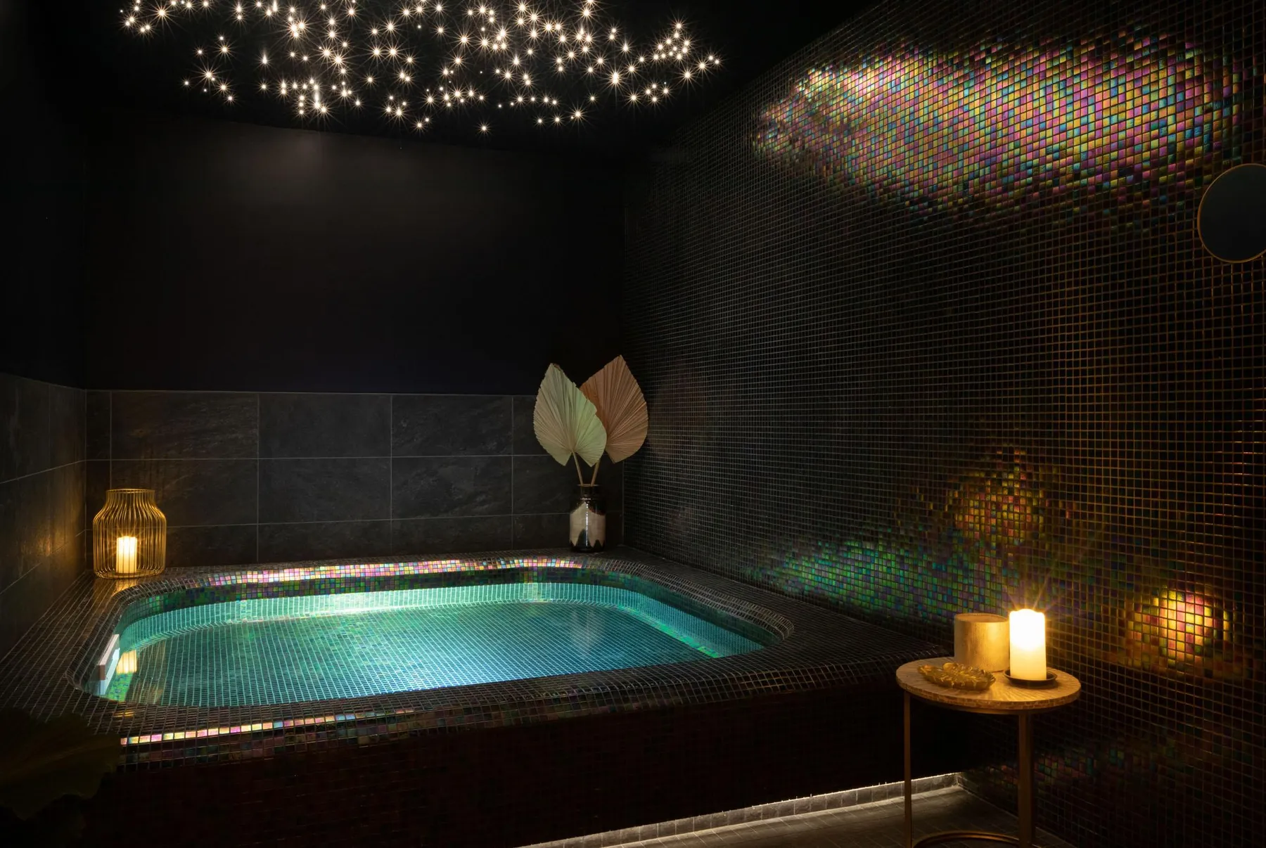 Indoor swimming pool illuminated with colorful mosaics on the walls and glowing stars on the ceiling