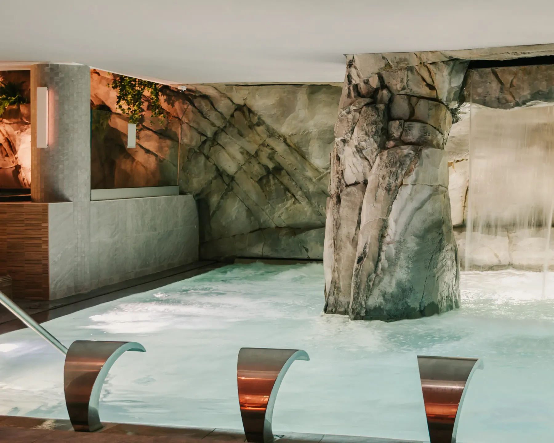 Indoor pool with artificial rocks and submerged metal benches