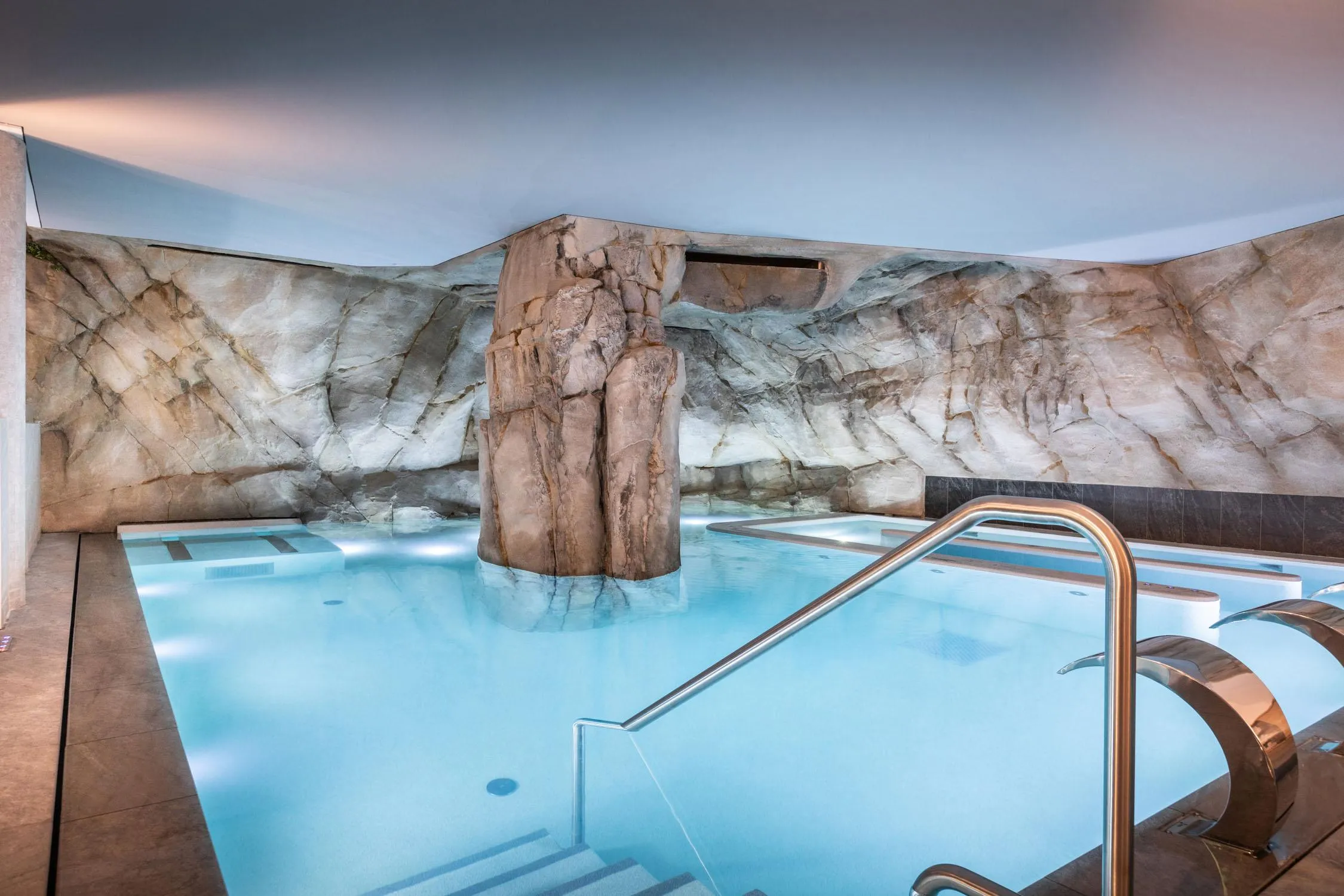 Innenpool mit großer Felswand und Metalltreppen für den Zugang