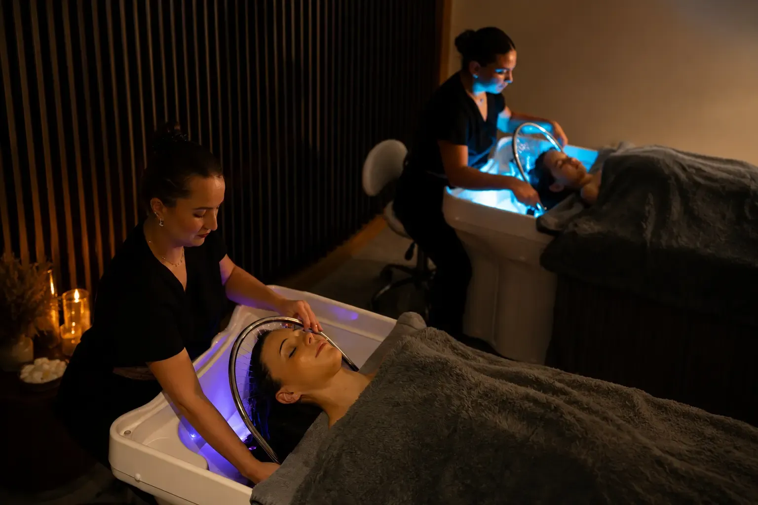 Zwei Personen, die liegen, erhalten eine Schönheitsbehandlung mit blauen Lichtgeräten in einem Wellness-Salon.